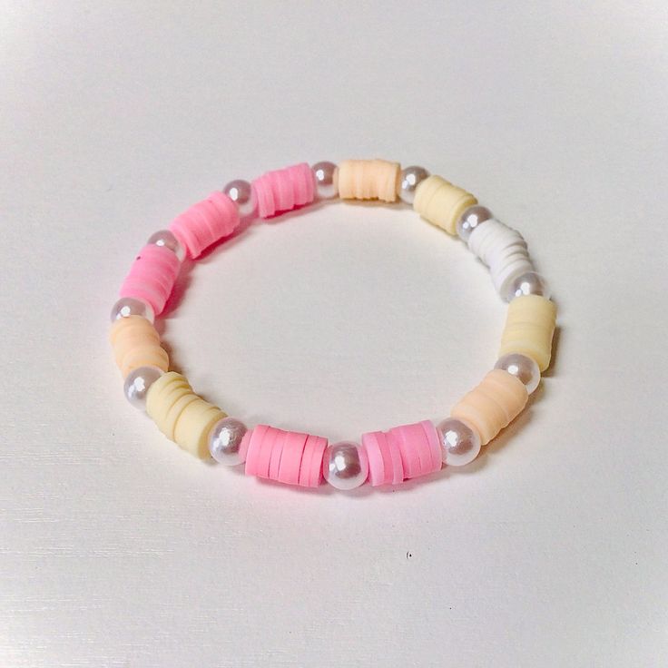 a bracelet made out of different colored beads on a white surface with a silver bead