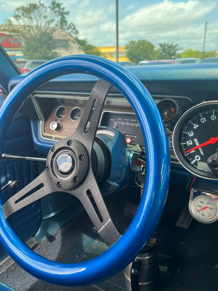 the interior of an old car with blue steering wheel and gauges on each side