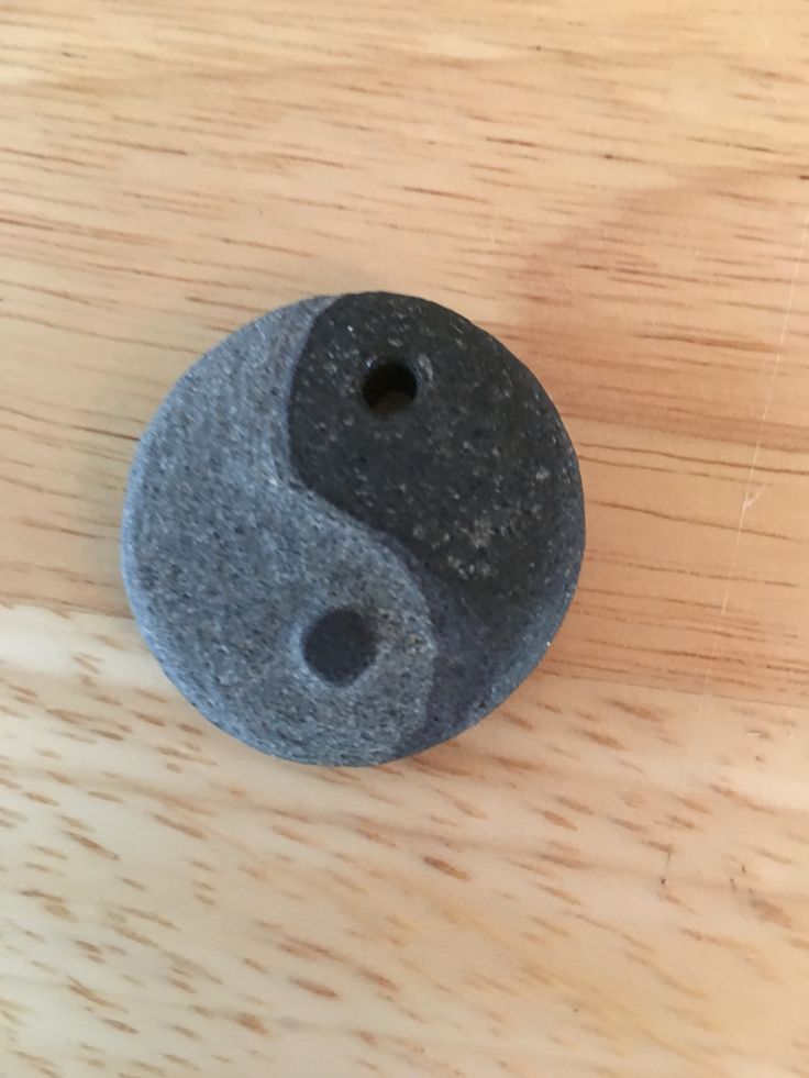 a black rock with a ying - o on it sitting on top of a wooden table