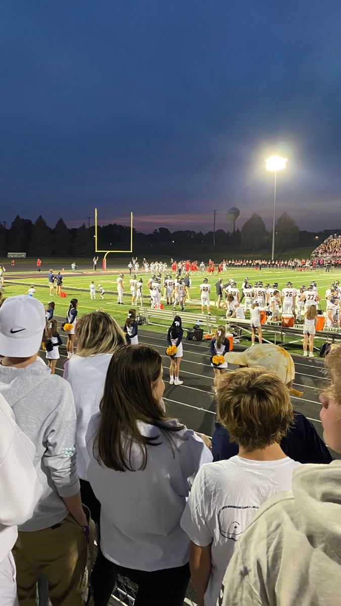 a group of young people standing on top of a field next to a football field