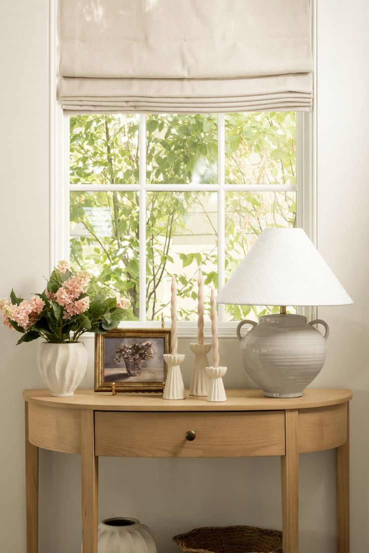 a table with vases and flowers on it in front of a window