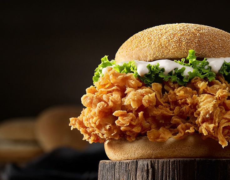 a chicken sandwich with lettuce and mayonnaise on a wooden board, ready to be eaten