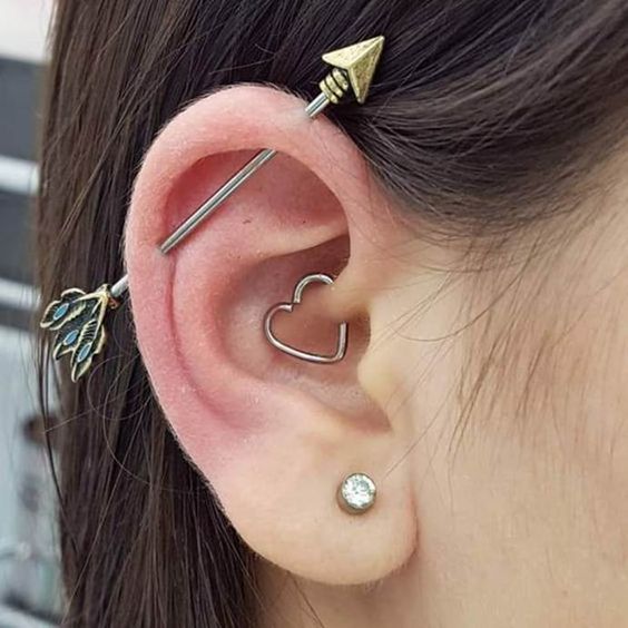 a woman wearing ear piercings with two small leaves on the side of her ear