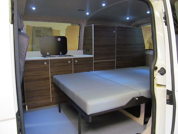 the inside of a van with a bed in it and cabinets on either side of the door