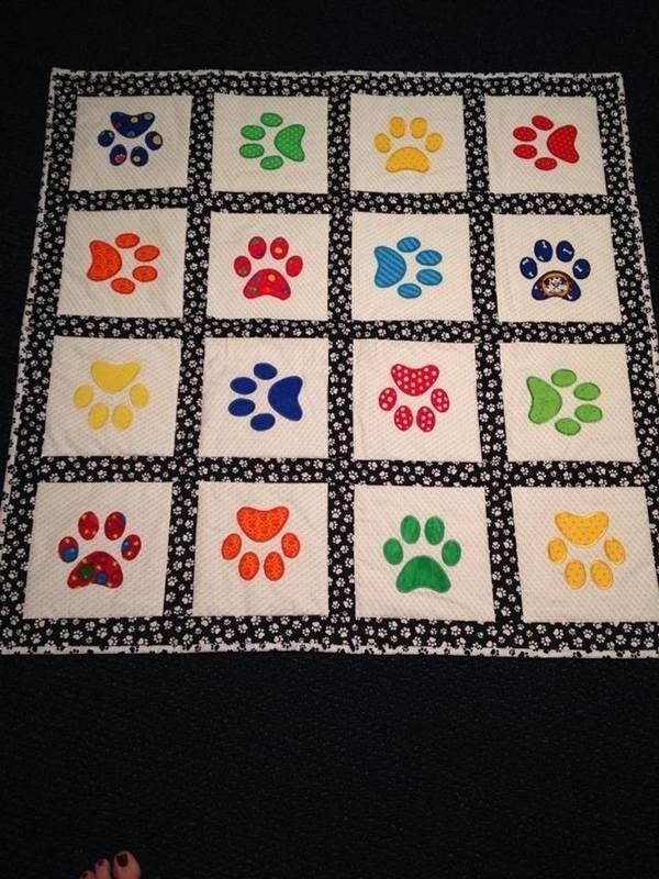 a quilted dog paw print is displayed on a black tablecloth with white squares