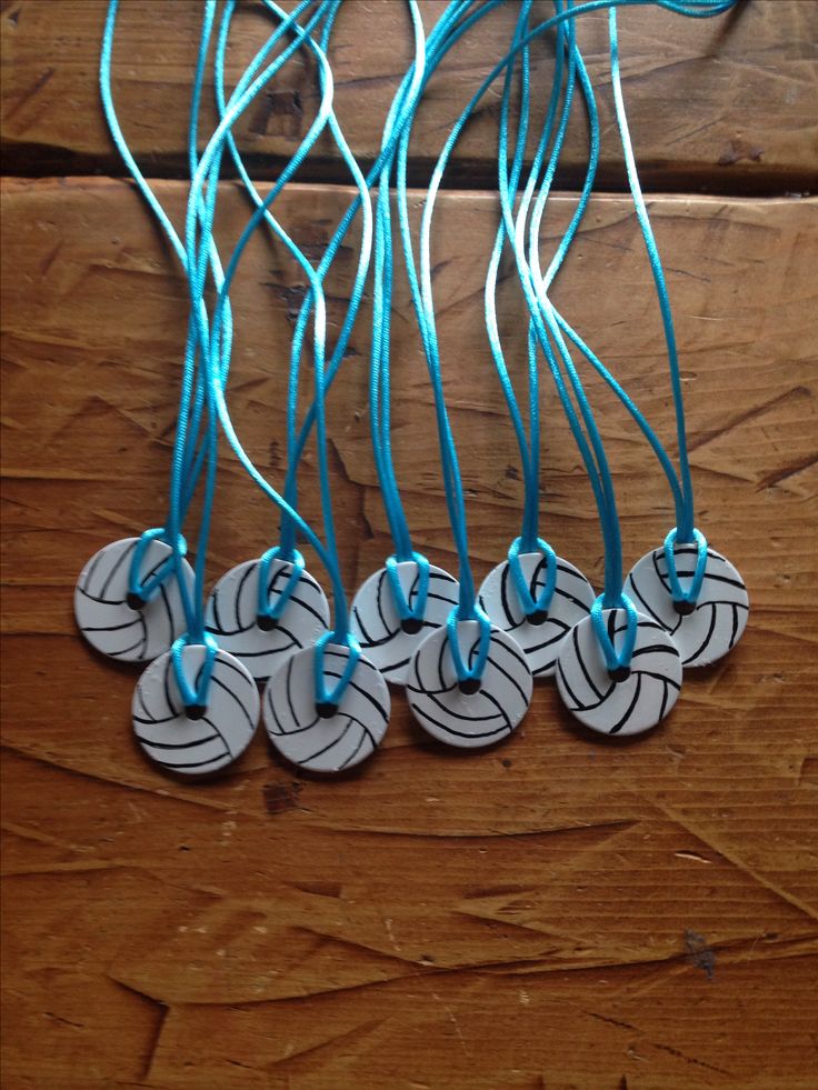 four necklaces with blue string attached to them on a wooden surface, one is white and the other is black