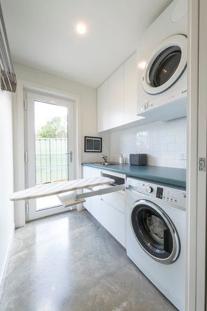 a washer and dryer in a small room with white walls, flooring and cabinets