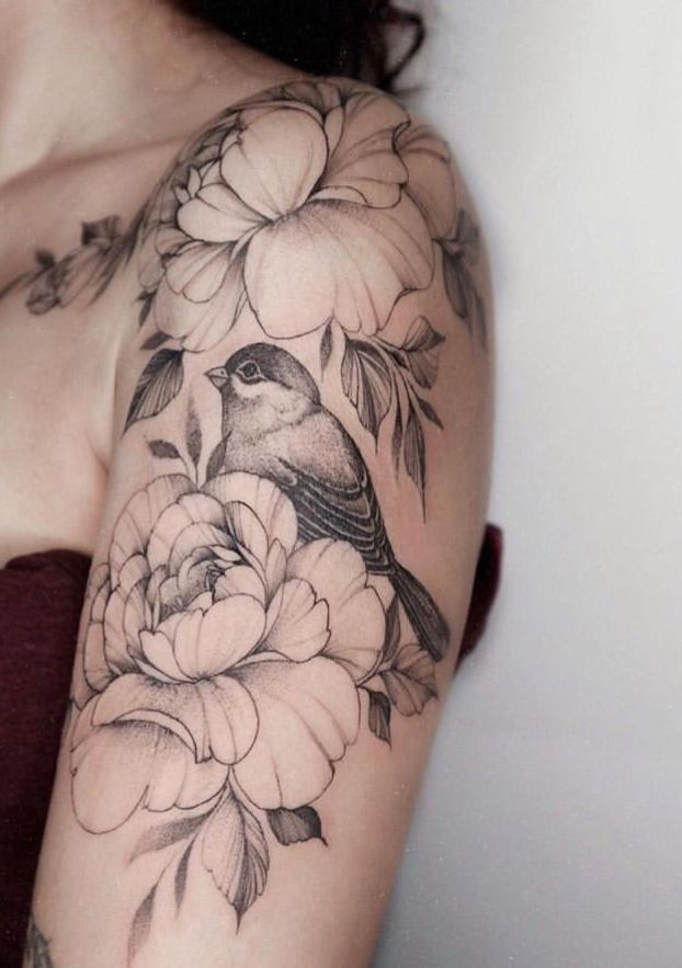 a woman's shoulder with flowers and a bird on it