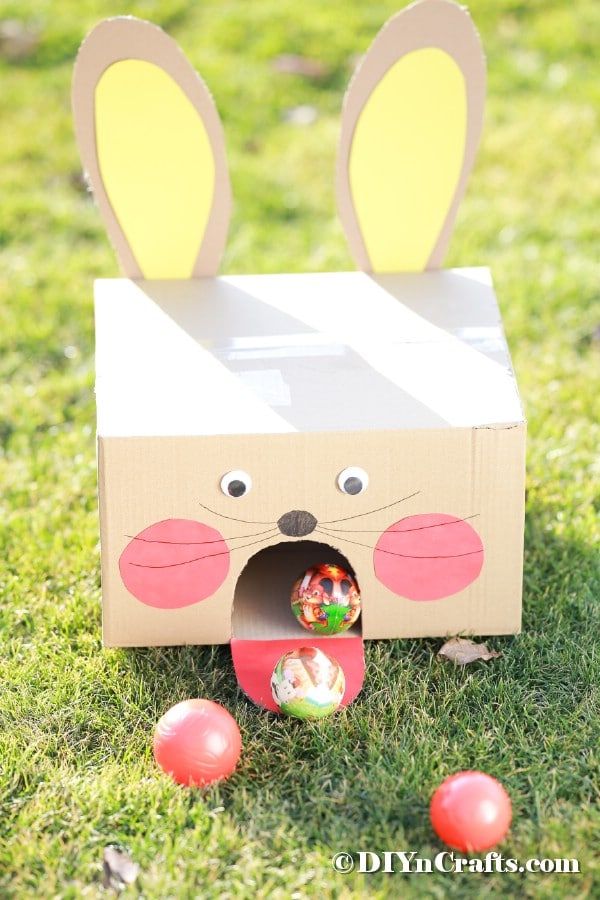 a cardboard box with bunny ears and eggs in the grass