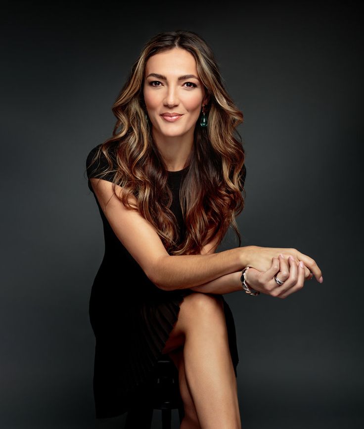 a beautiful woman sitting on top of a stool in a black shirt and skirt with her legs crossed