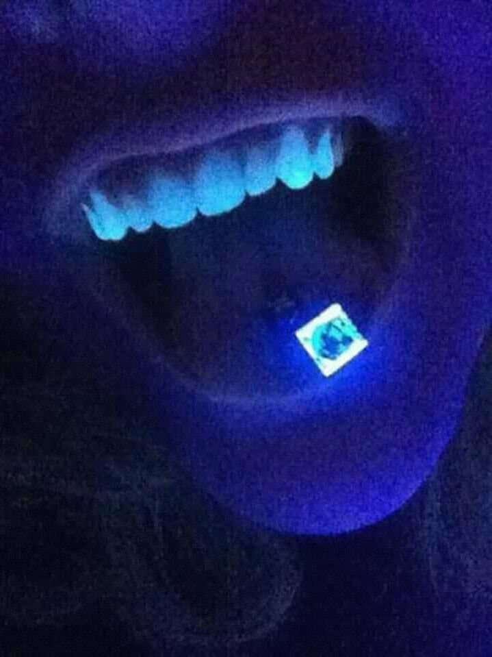 a toothbrush with glowing teeth in it's mouth is lit up by blue light