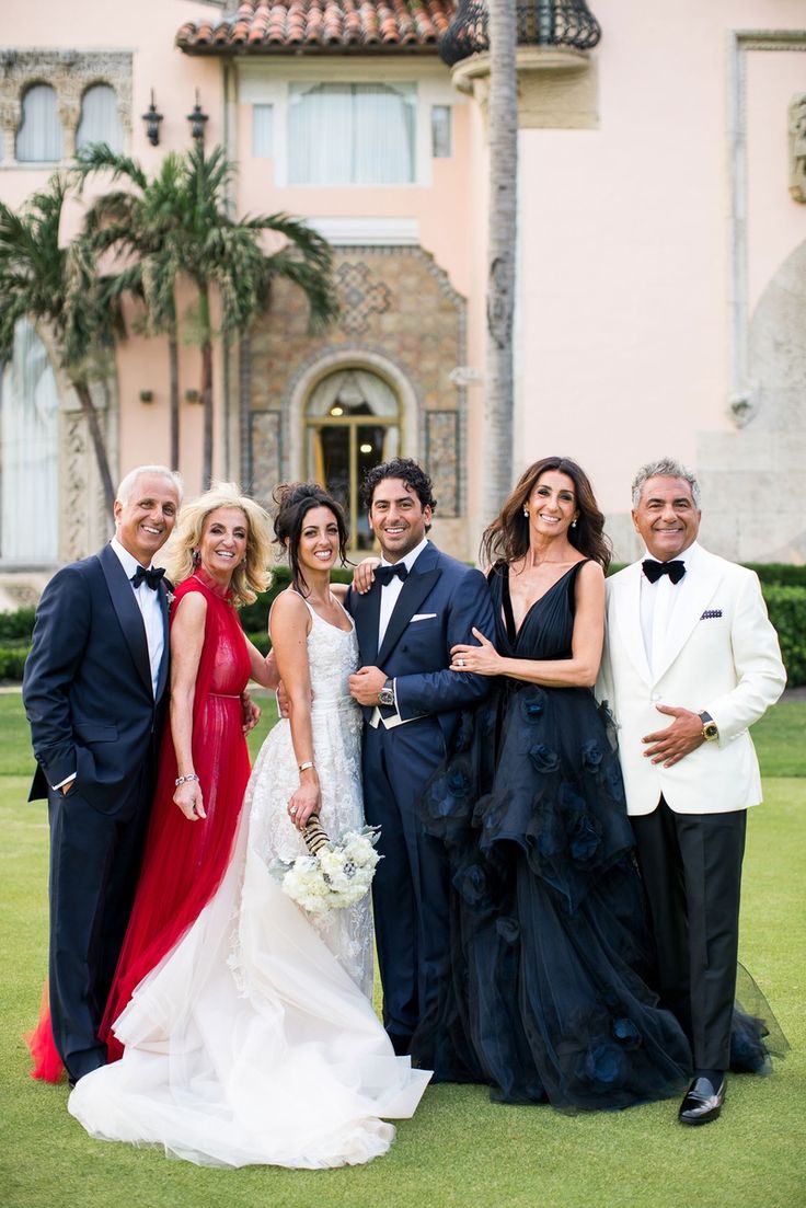 a group of people standing next to each other in front of a building with palm trees