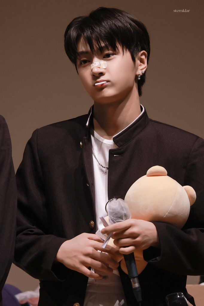 a young man holding a stuffed animal in his right hand and wearing a black jacket