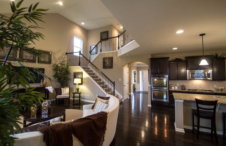 a living room filled with furniture next to a kitchen and dining room table in front of an open floor plan