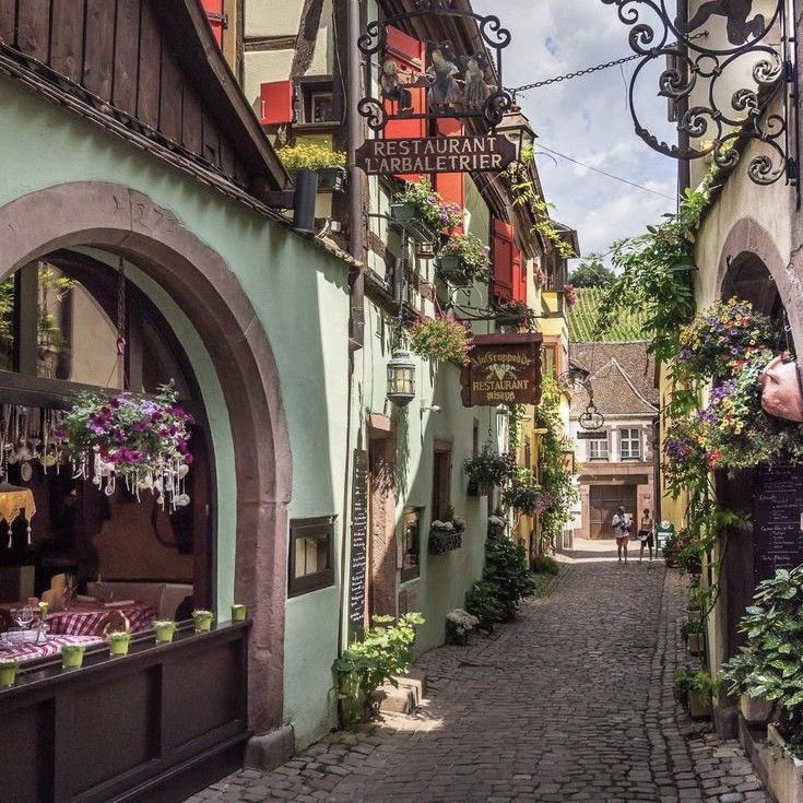 an alley way with buildings and flowers on the side, in germany's old town