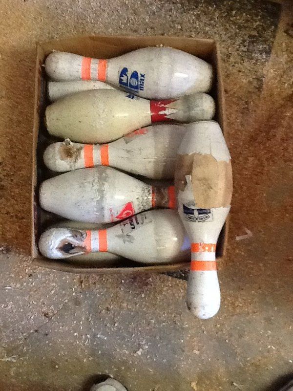 six bowling pins in a box on the ground