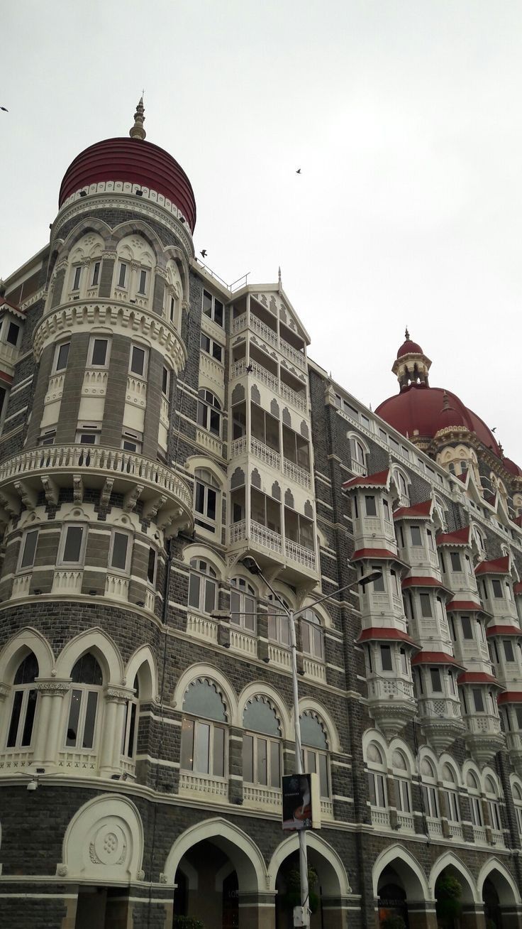 an old building with many windows and balconies on the top floor, in front of a cloudy sky