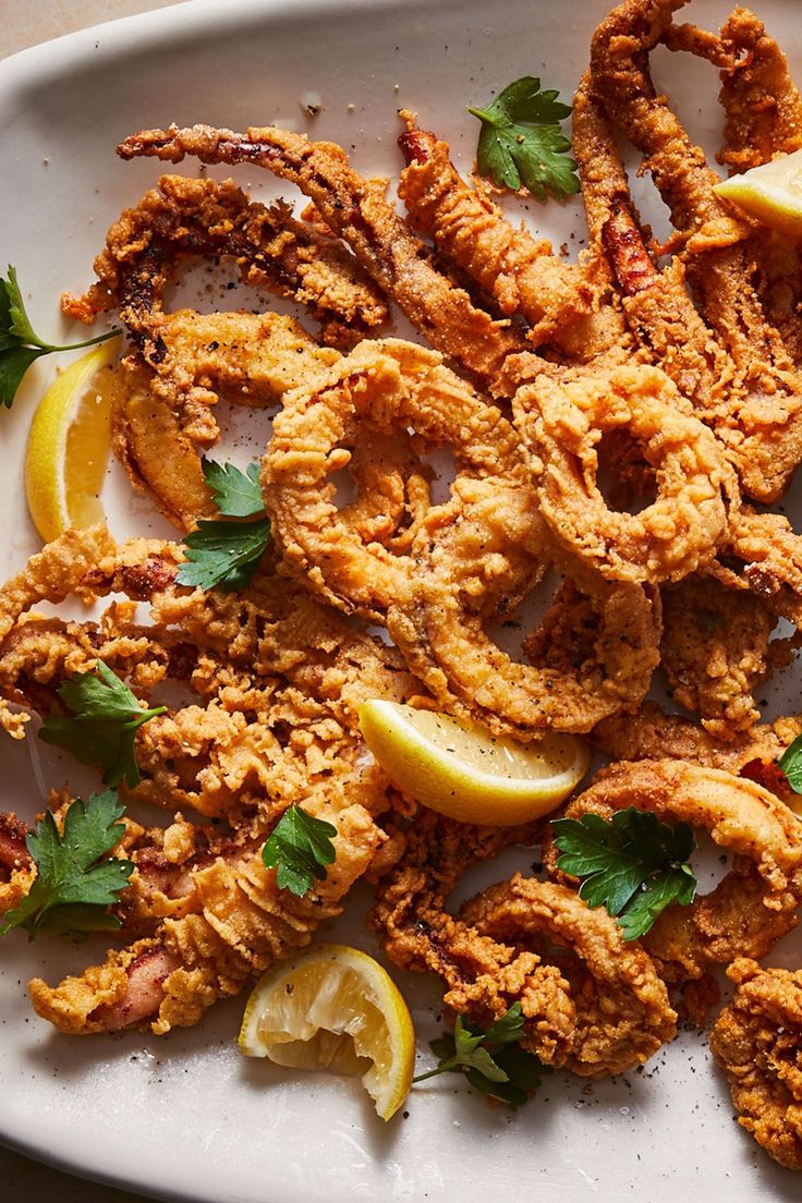 fried food on a plate with lemon wedges and parsley