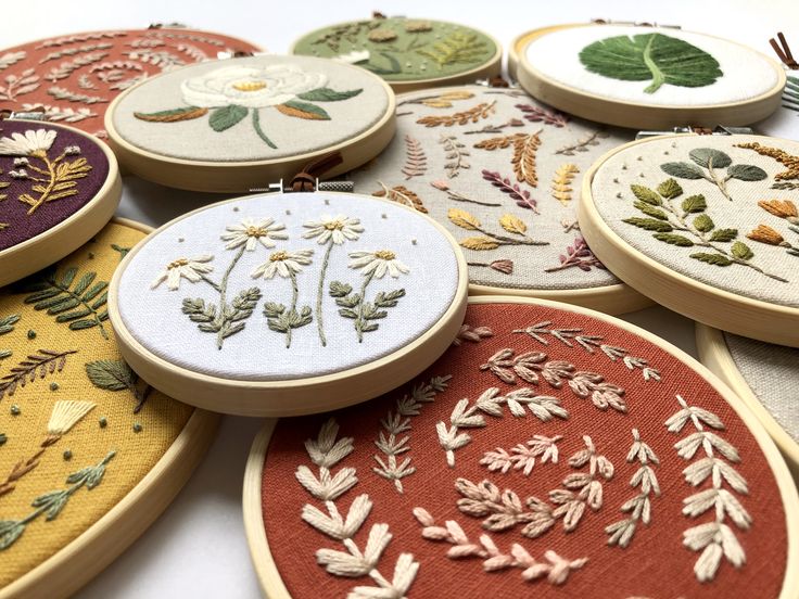 many different types of embroidery on wooden hoops with leaves and flowers in the center