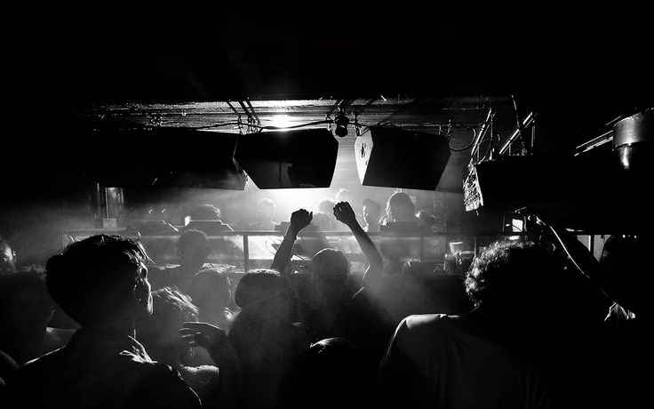 a group of people standing in front of a stage with their hands up and lights on