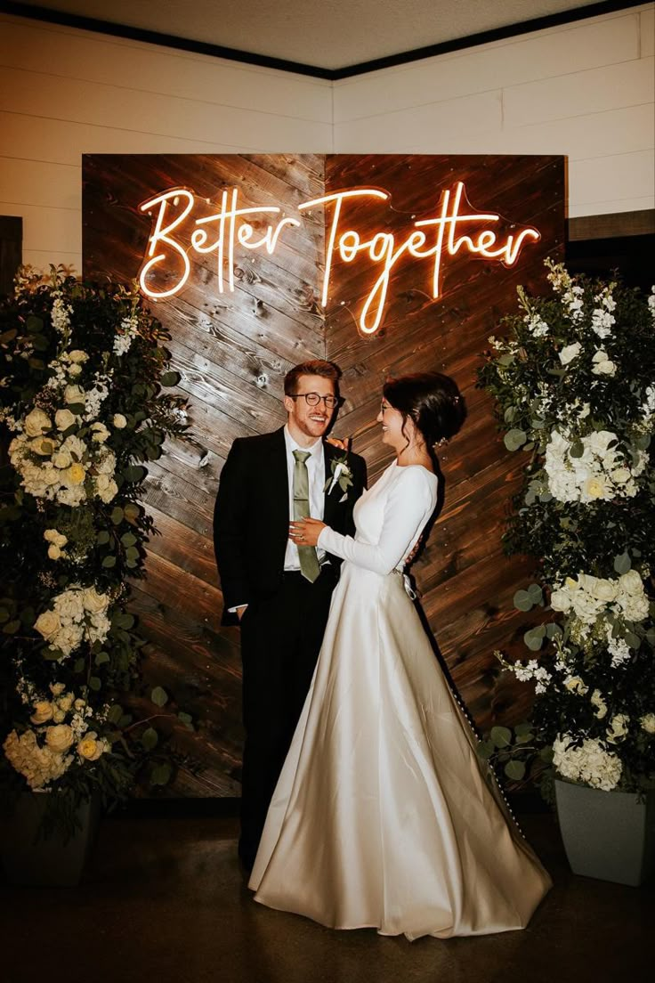 a bride and groom standing in front of a sign that says better together