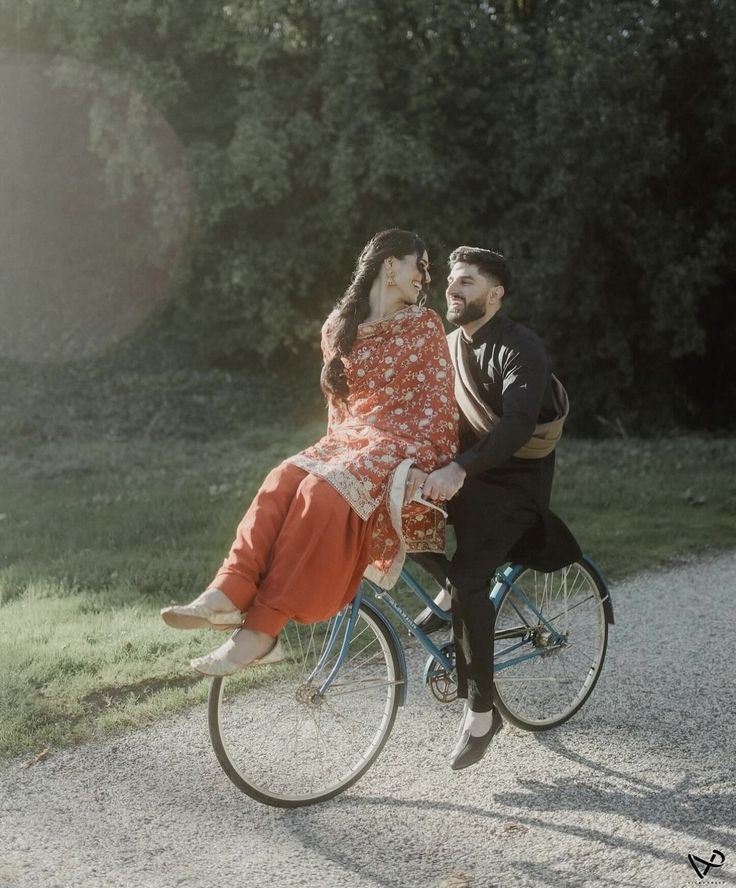 a man riding on the back of a bike next to a woman in an orange dress