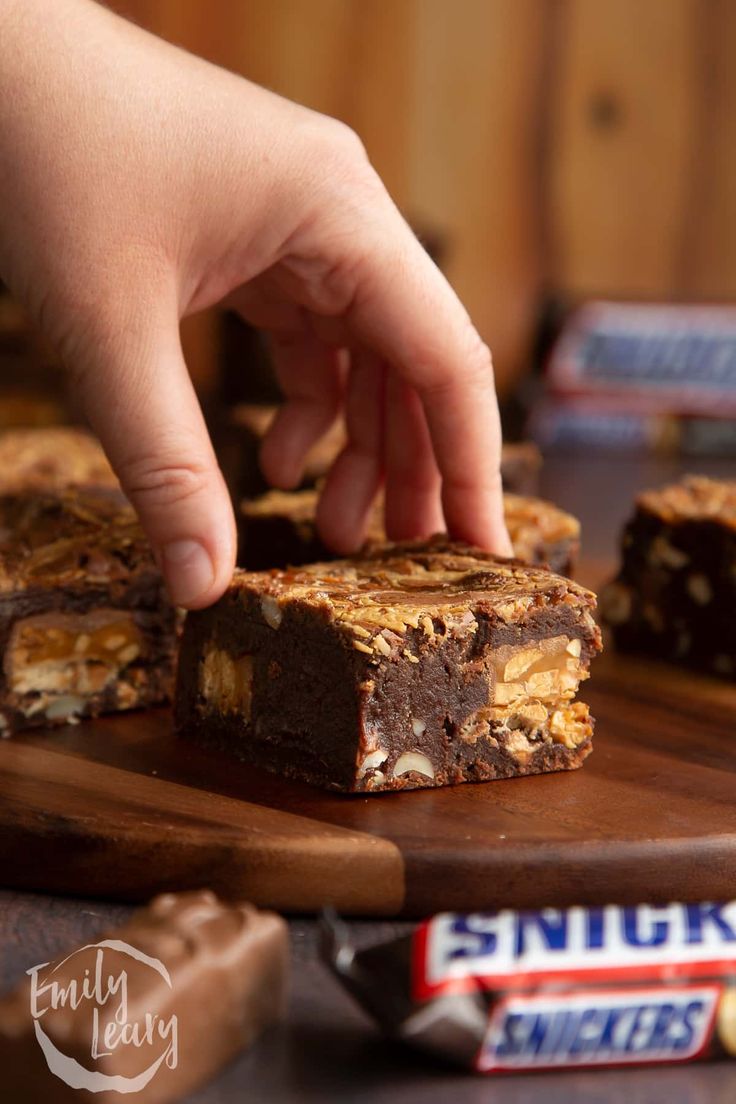 a person reaching for some food on a cutting board with candy bars in the background