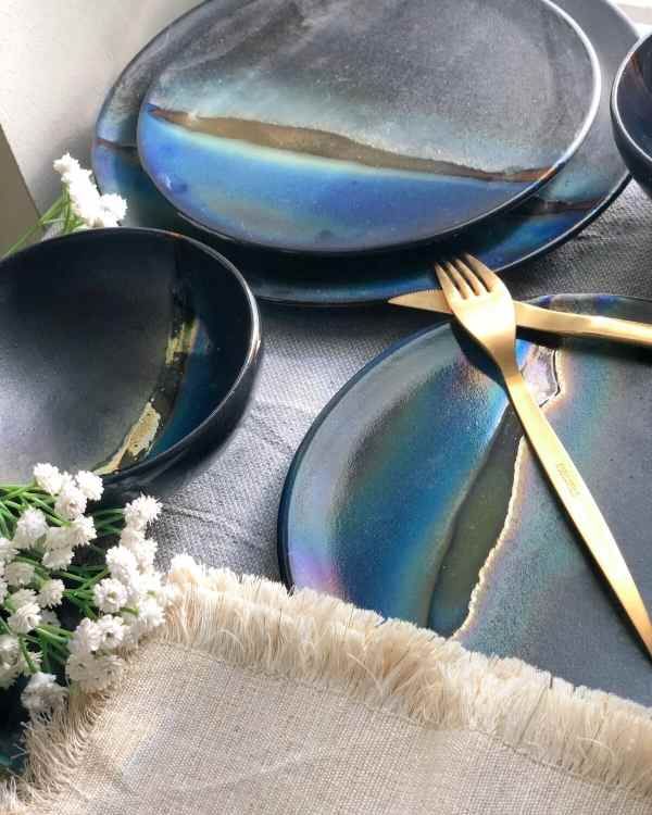 the table is set with blue plates and silverware on it, along with white flowers