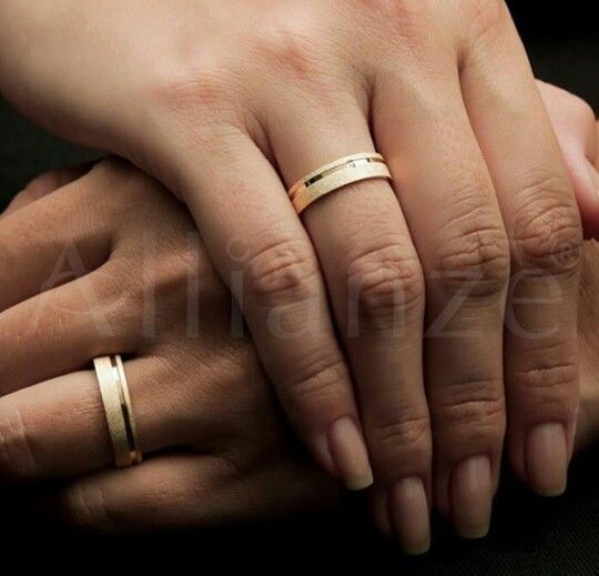 two people holding hands with gold rings on their fingers