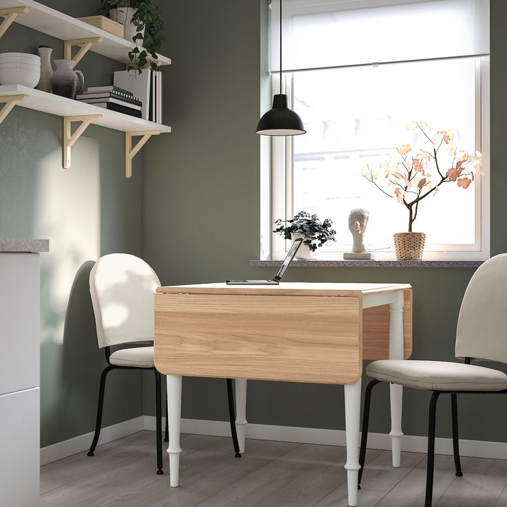 two chairs and a table in front of a window with plants on the windowsill