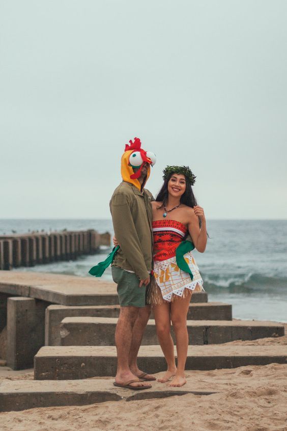 a man and woman in costumes standing on the beach next to some steps looking at the ocean