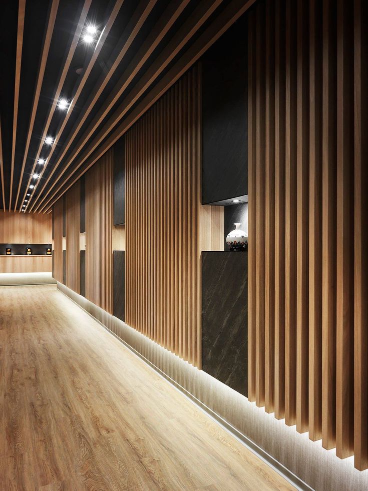 an empty room with wooden slats on the walls and wood flooring in front of it