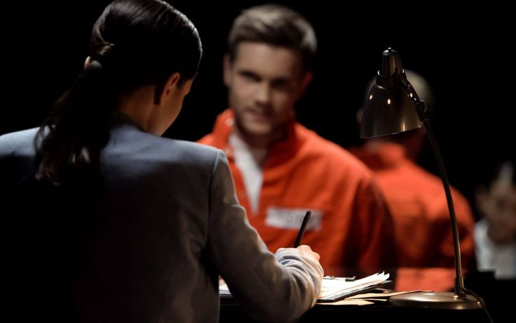 a woman sitting at a desk writing in front of a man