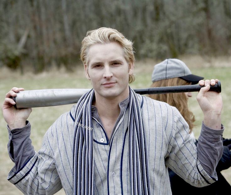 a man holding a baseball bat over his shoulder while standing next to a woman in a field