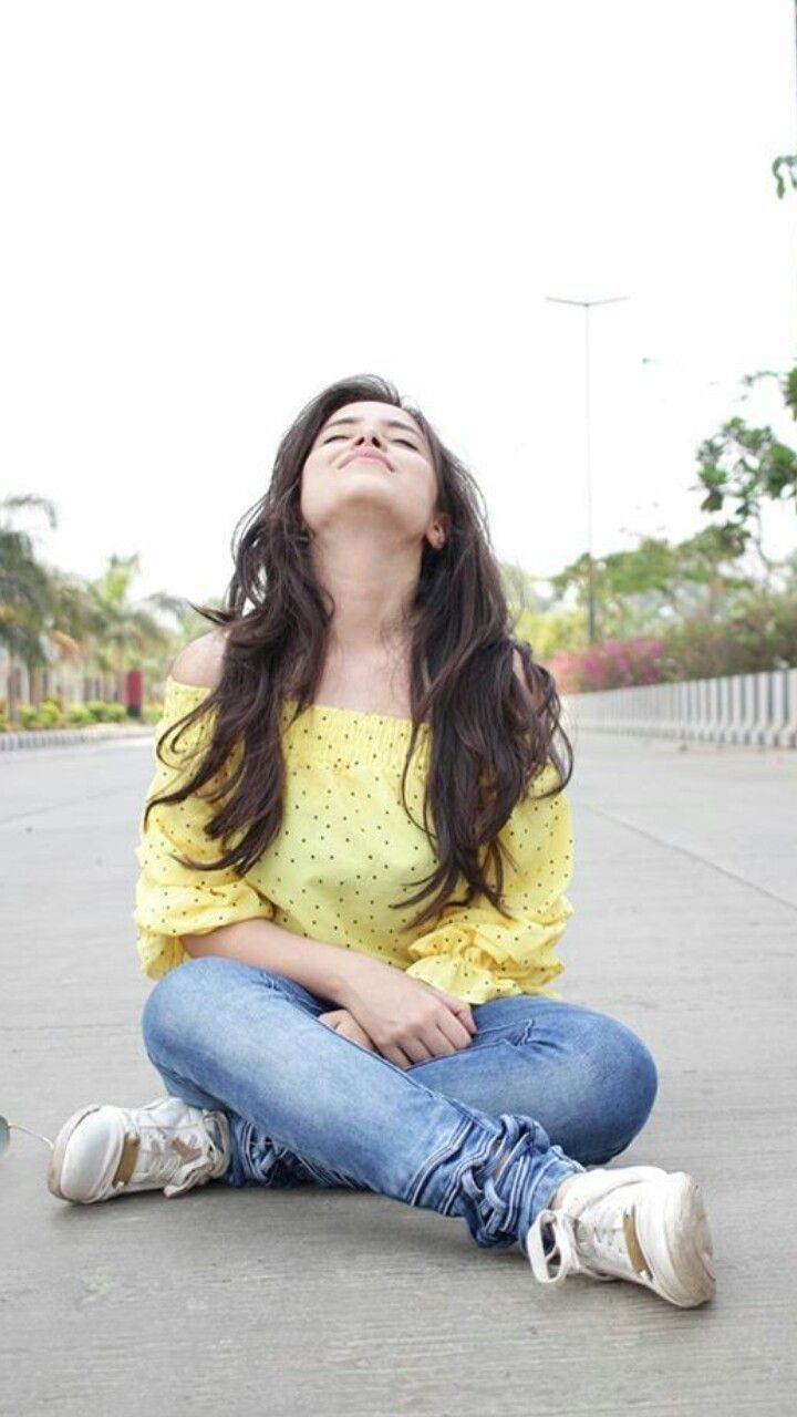 a woman sitting on the ground with her eyes closed, looking up at something in the air