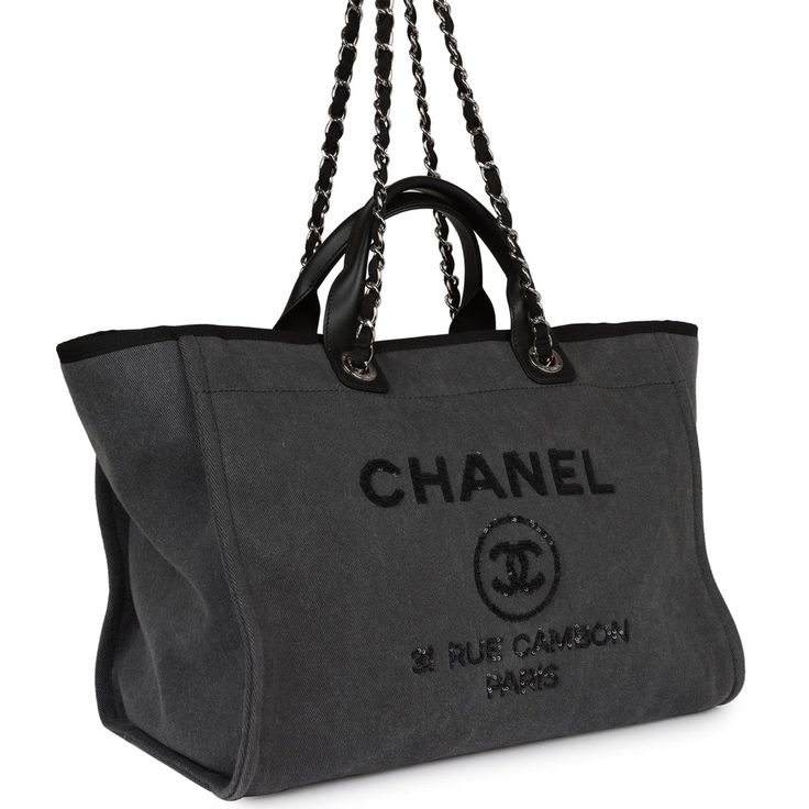 This Medium Chanel Deauville Tote is made of Dark Grey Denim with silver hardware, large CC signature and Chanel logo on front, interwoven silver tone chain link shoulder straps, and top handle.The interior is lined in black fabric and has two open pockets on the front wall and a zipper pocket with a Chanel pull on the rear wall.   Collection: 23-series (2016-17)Origin: ItalyCondition: New and never worn Accompanied by: Chanel box, Chanel dustbag, ribbon, COA, and retail UPC Measurements: 15" width x 12" height 8" depth; 12" shoulder straps 4" top handles Tote Bag Chanel, Chanel Tote Bag, Chanel Box, Front Wall, Chanel Logo, Grey Denim, Vuitton Bag, Sierra Leone, Shopping Tote