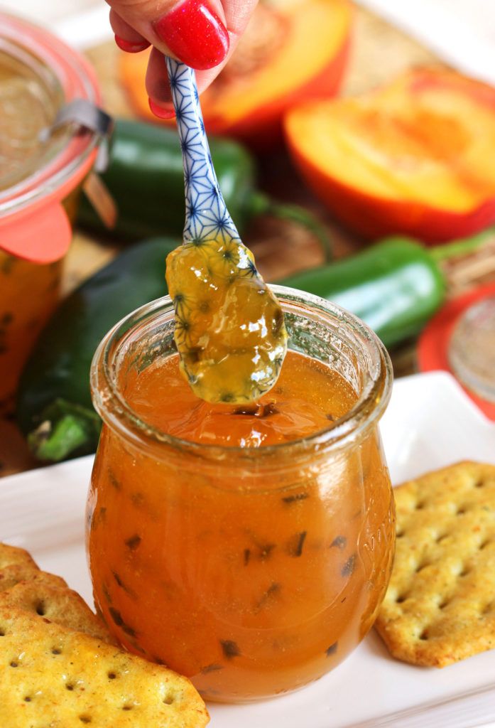 a person is holding a pickle over a jar of pickles and crackers