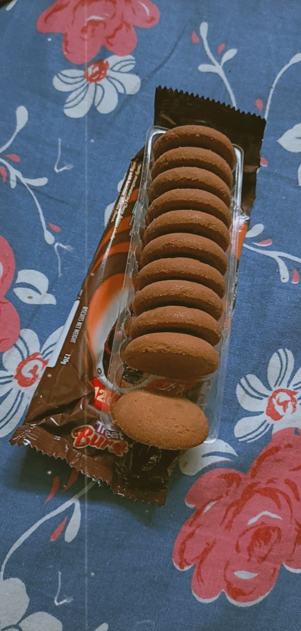 a box of cookies sitting on top of a blue floral table cloth with a bag of them