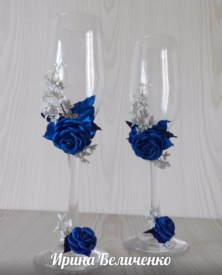 two wine glasses with blue roses and silver leaves on the stems, one is empty