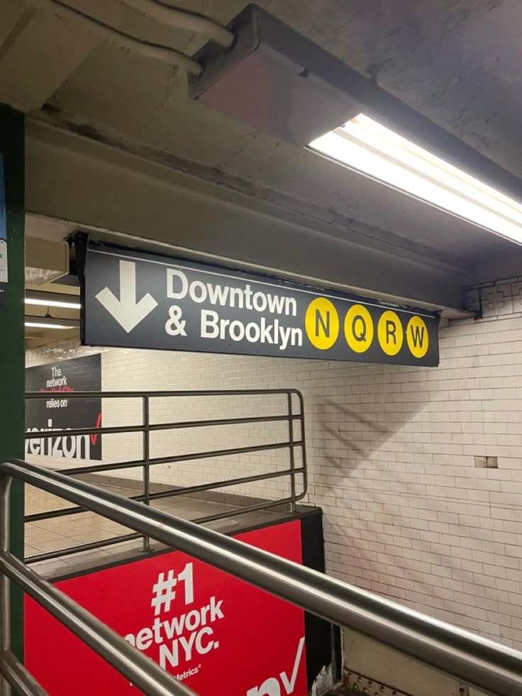 a subway station with several signs on the wall and stairs leading up to the platforms