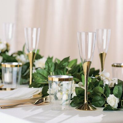 the table is set with champagne glasses and greenery