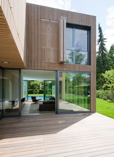 a large wooden deck with sliding glass doors leading to the back of a modern home