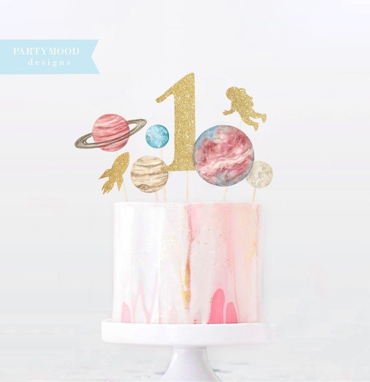 a pink and gold cake with the number one on top, surrounded by space themed decorations