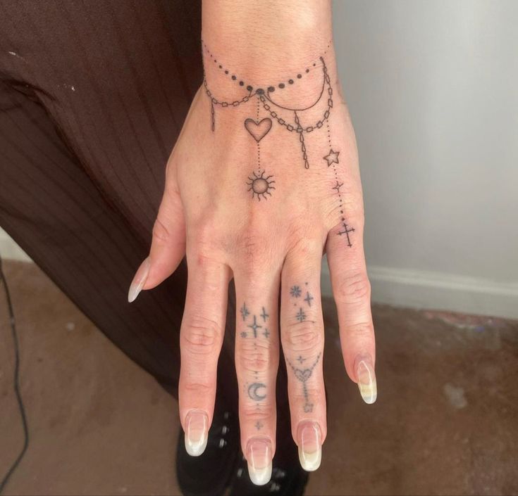 a woman's hand with tattoos on it and a chain around her wrist,