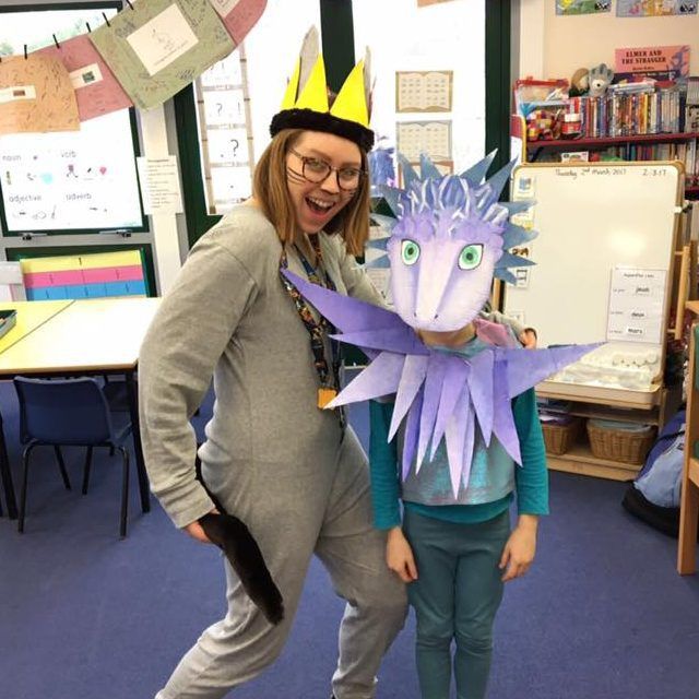 a woman standing next to a child wearing a paper dragon mask and holding it up