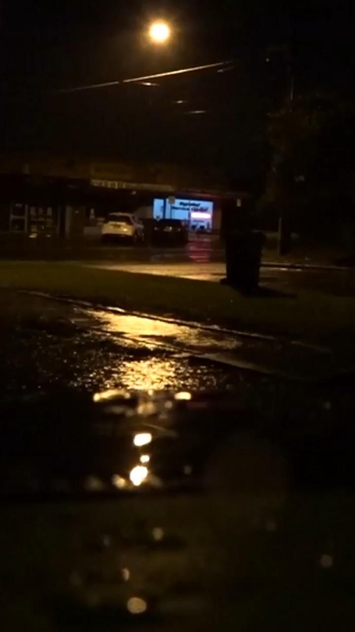 a street at night with the lights on and water puddles in front of it