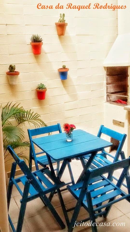 an outdoor table and chairs with potted plants on the wall in front of it