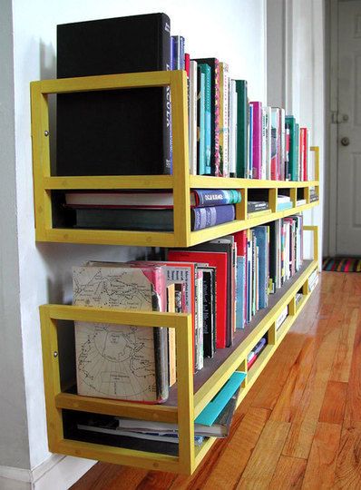 a bookshelf filled with lots of books on top of a hard wood floor