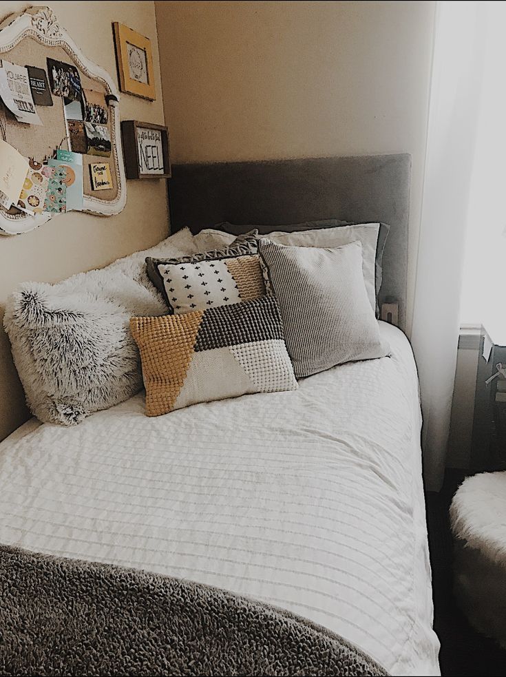 a bed with many pillows on it in a room next to a window and pictures