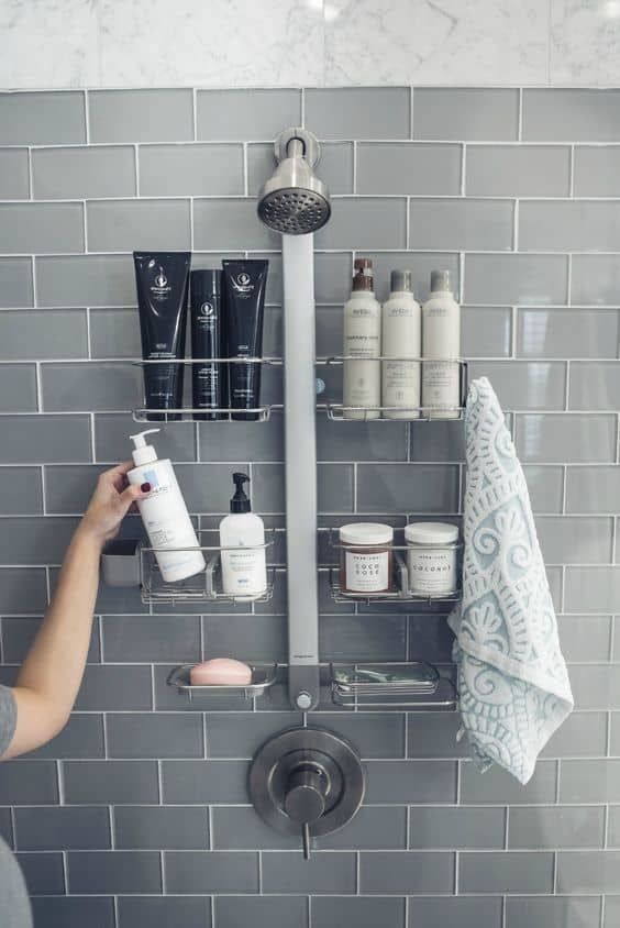 a person holding a spray bottle in front of a bathroom wall mounted shower faucet